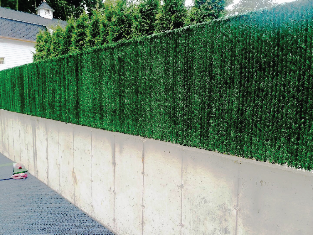 Artificial Greenery on chain link fence on top of concrete wall